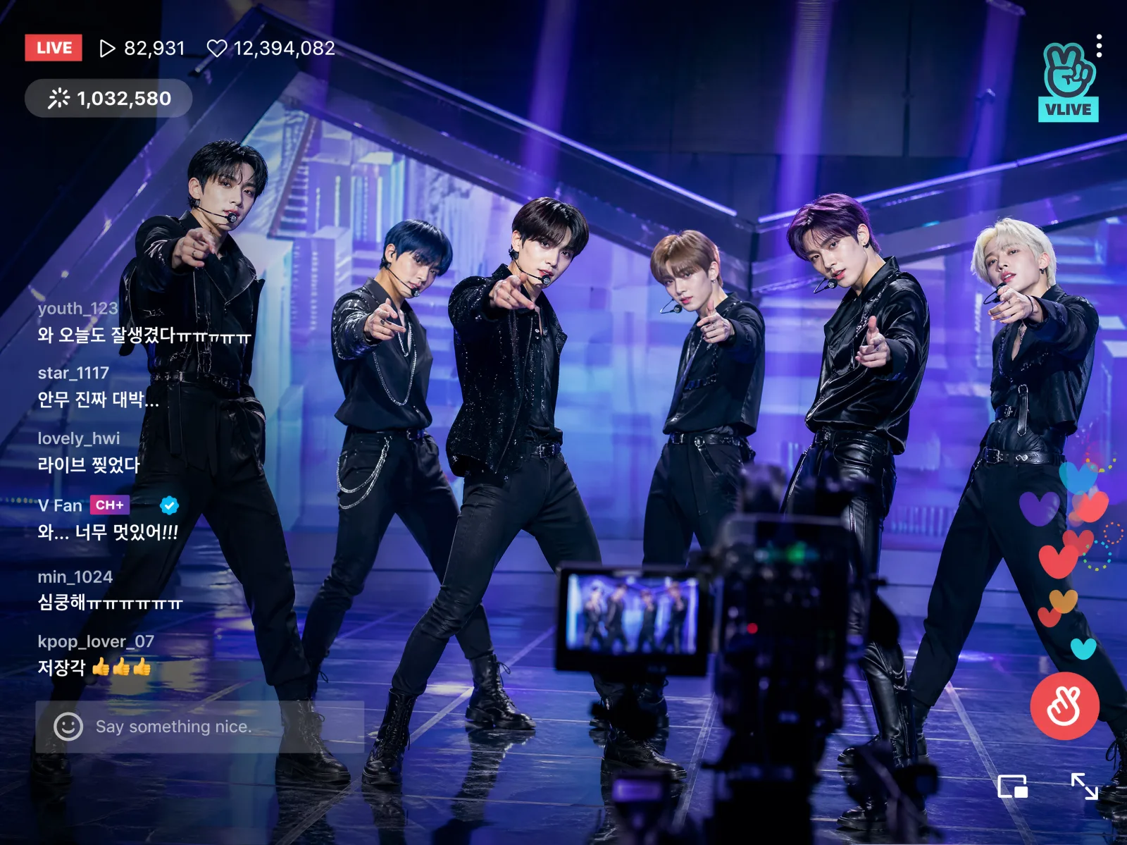 K-pop group performing on a futuristic stage with live chat overlay